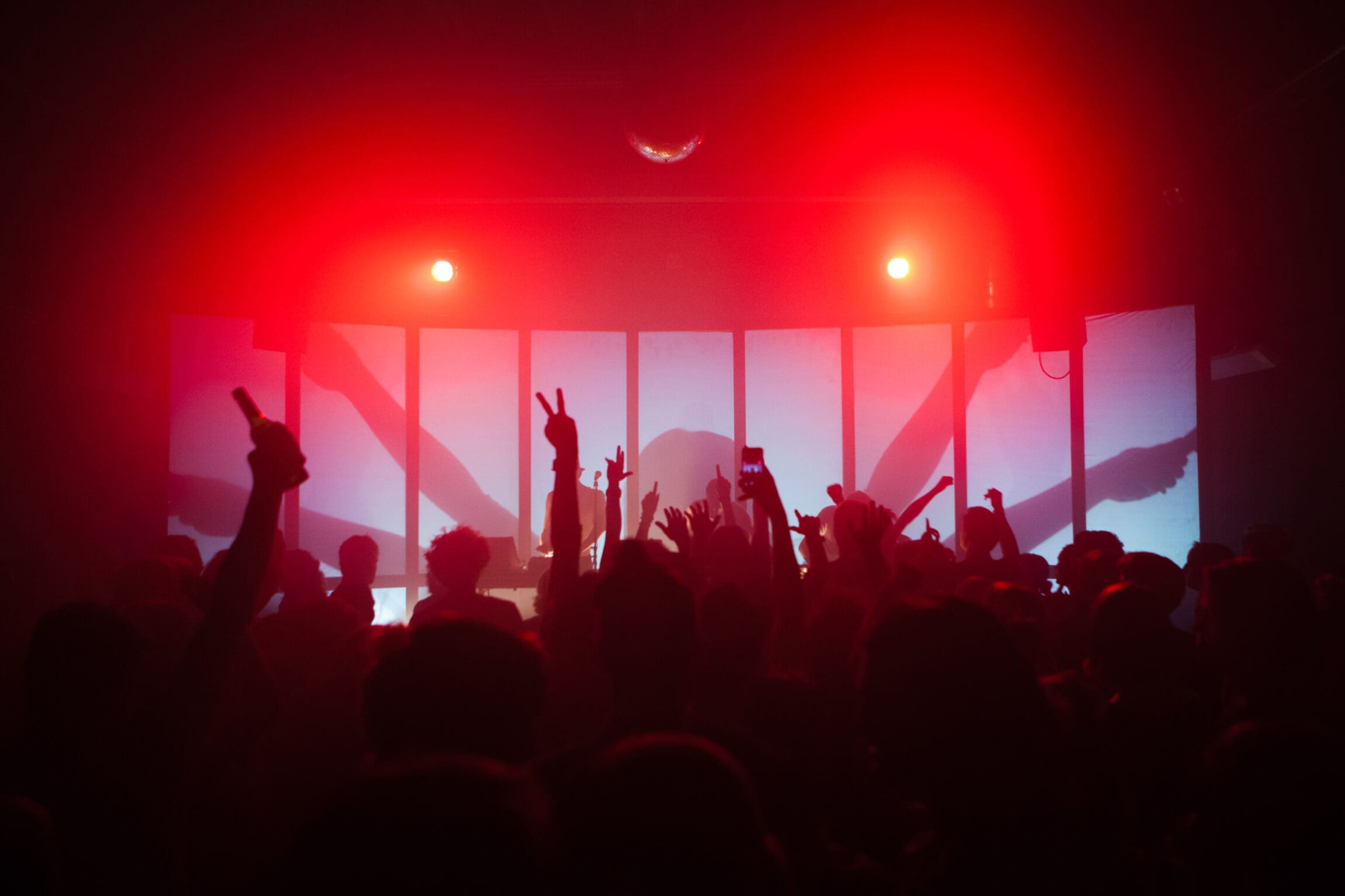 The best bars in Amsterdam | A crowd of people dance in front of a stage with red lights on them.