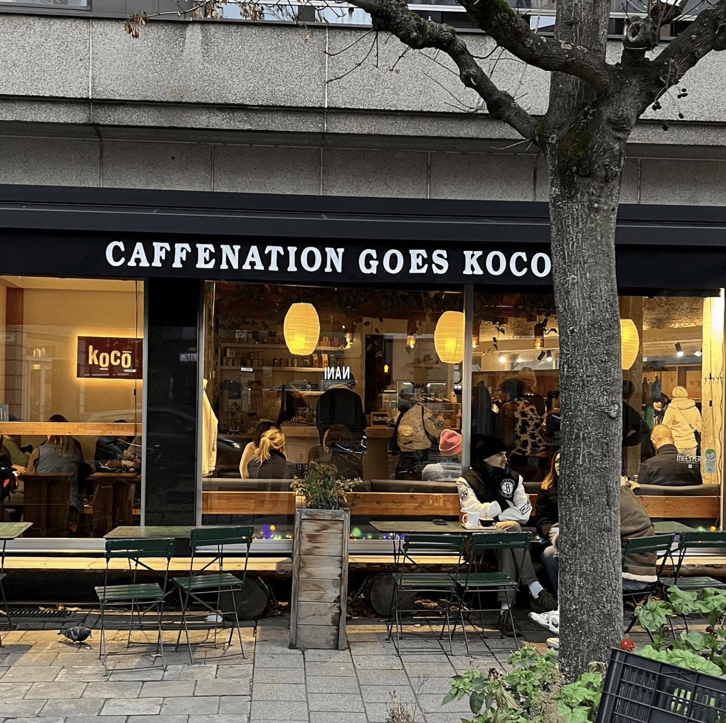 The best co-working spaces in Amsterdam for remote working | Outside of the Caffenation cafe with green metal tables outside.