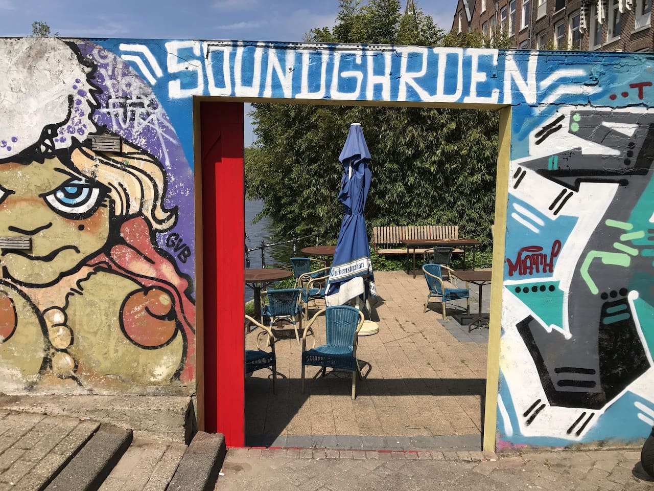 The best bars in Amsterdam | The outdoor Soundgarden entrance leads to a deck with chairs and an umbrella looking over the canal.