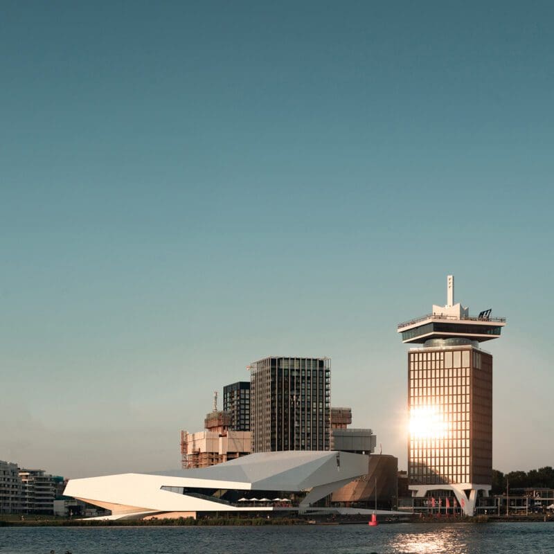 The best museums and art galleries in Amsterdam | The angular white facade of The Eye Filmmuseum in front of a blue sky by the waterfront in Amsterdam Noord