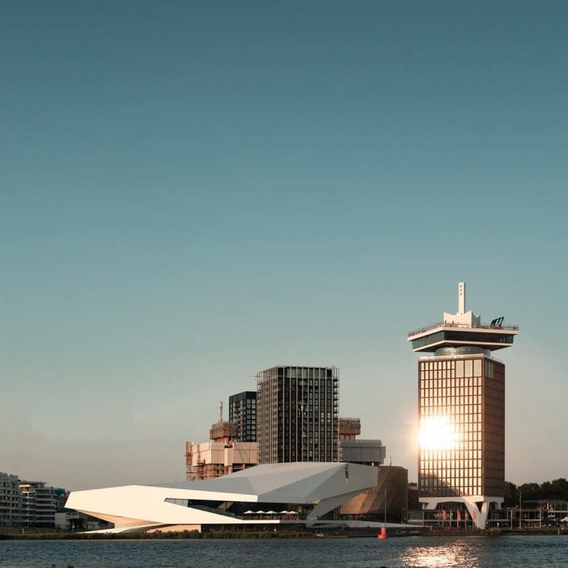 Amsterdam city guide | angular white facade of The Eye Filmmuseum in front of a blue sky by the waterfront in Amsterdam Noord