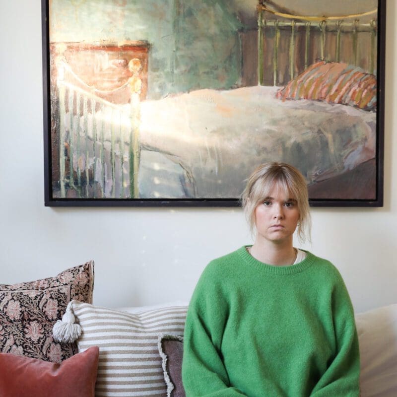 Writer Hannah Turner on her sofa, wearing a green jumper