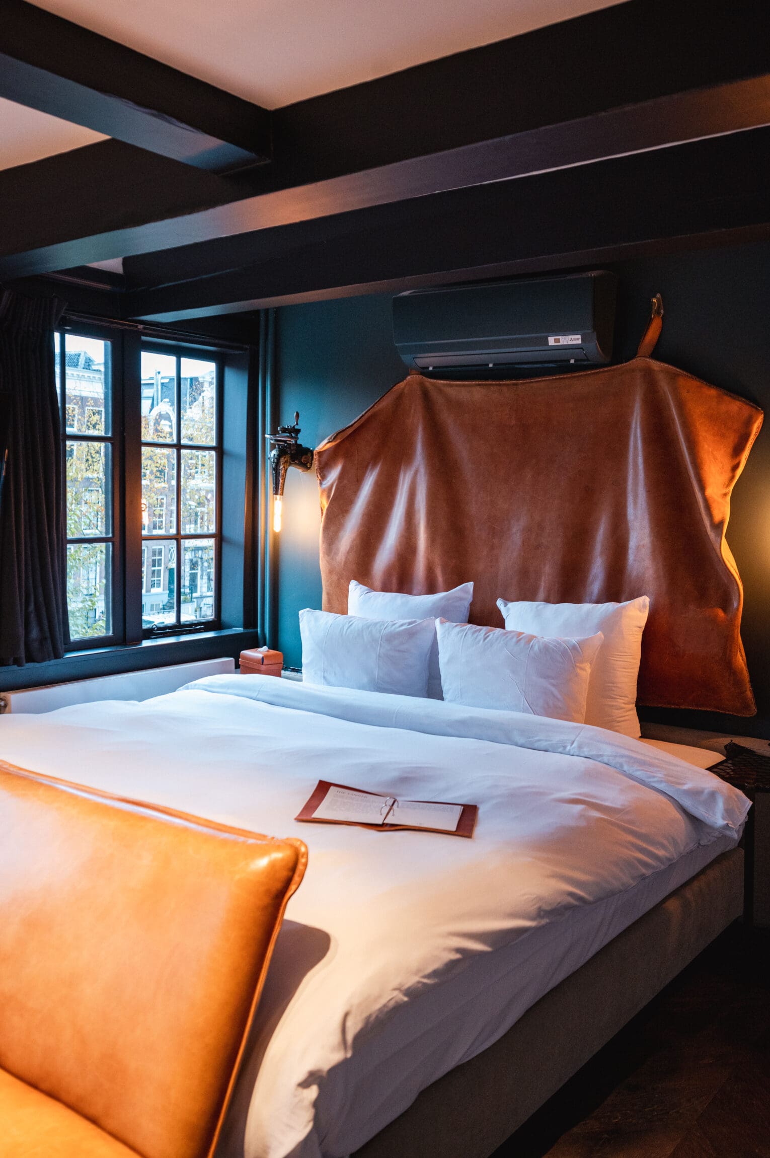 The best hotels in Amsterdam | a bed with a statement leather headboard
