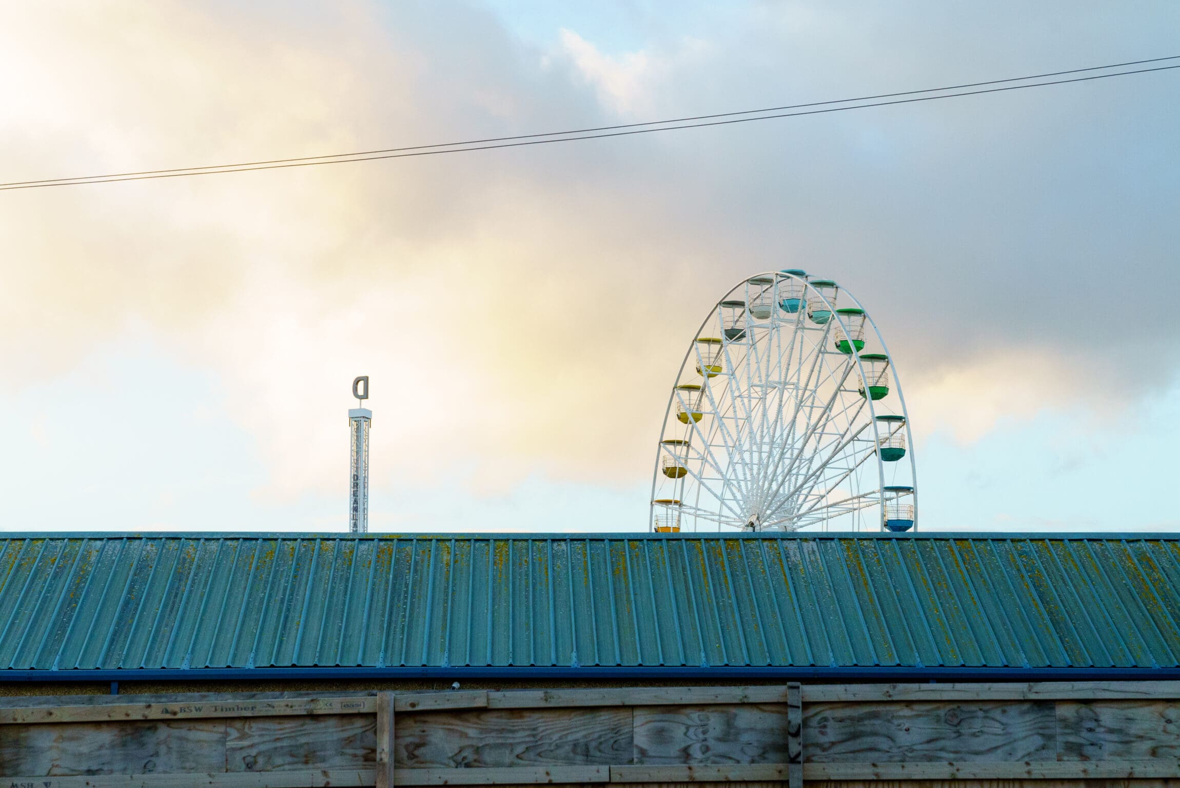 An alternative literary tour of the Kent coastline | A ferris wheel peering above a blue metal roof in Margate