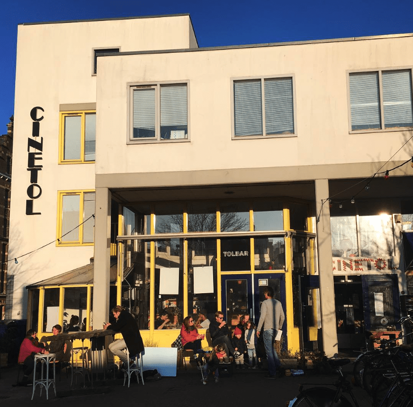 The best bars in Amsterdam | the lively exterior at Tolbar, bathed in warm light