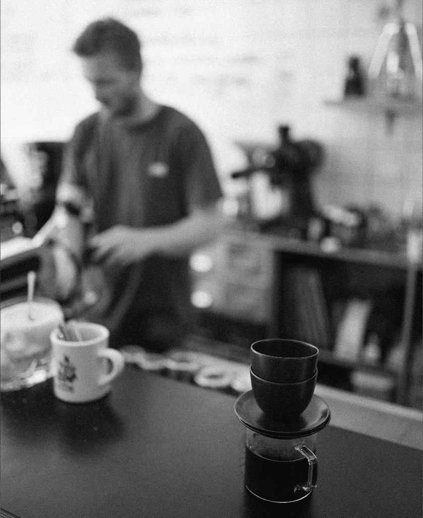 Where to get the best coffee in Amsterdam | Coffee filtering on the counter with somebody in the background making espresso