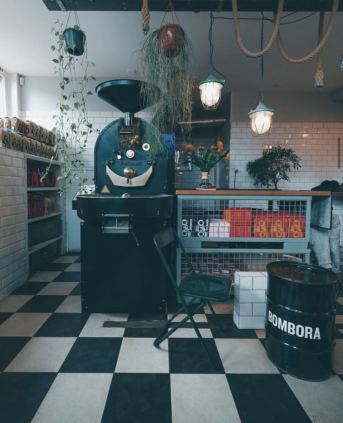 Where to get the best coffee in Amsterdam | Coffee roaster on a checkered floor with flowers and plants around the space