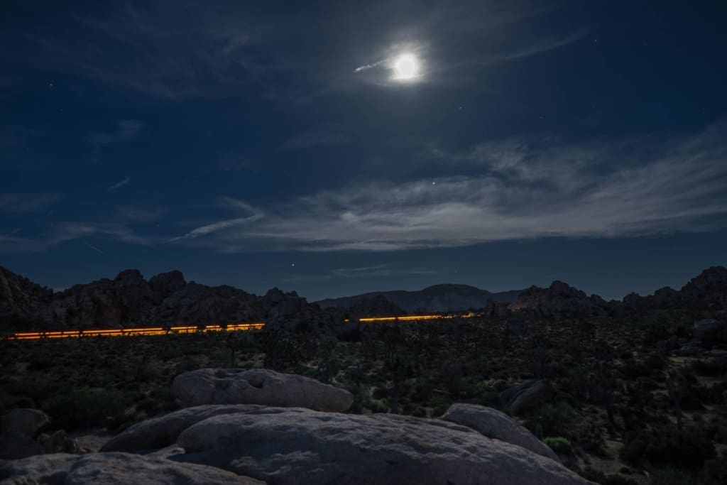 The return of European sleeper trains | A train whizzes through a dark landscape at night beneath a full moon