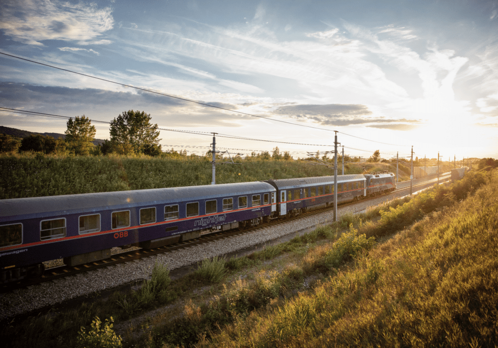 The return of European sleeper trains | The ÖBB Nightjet travelling through a green field at sunset