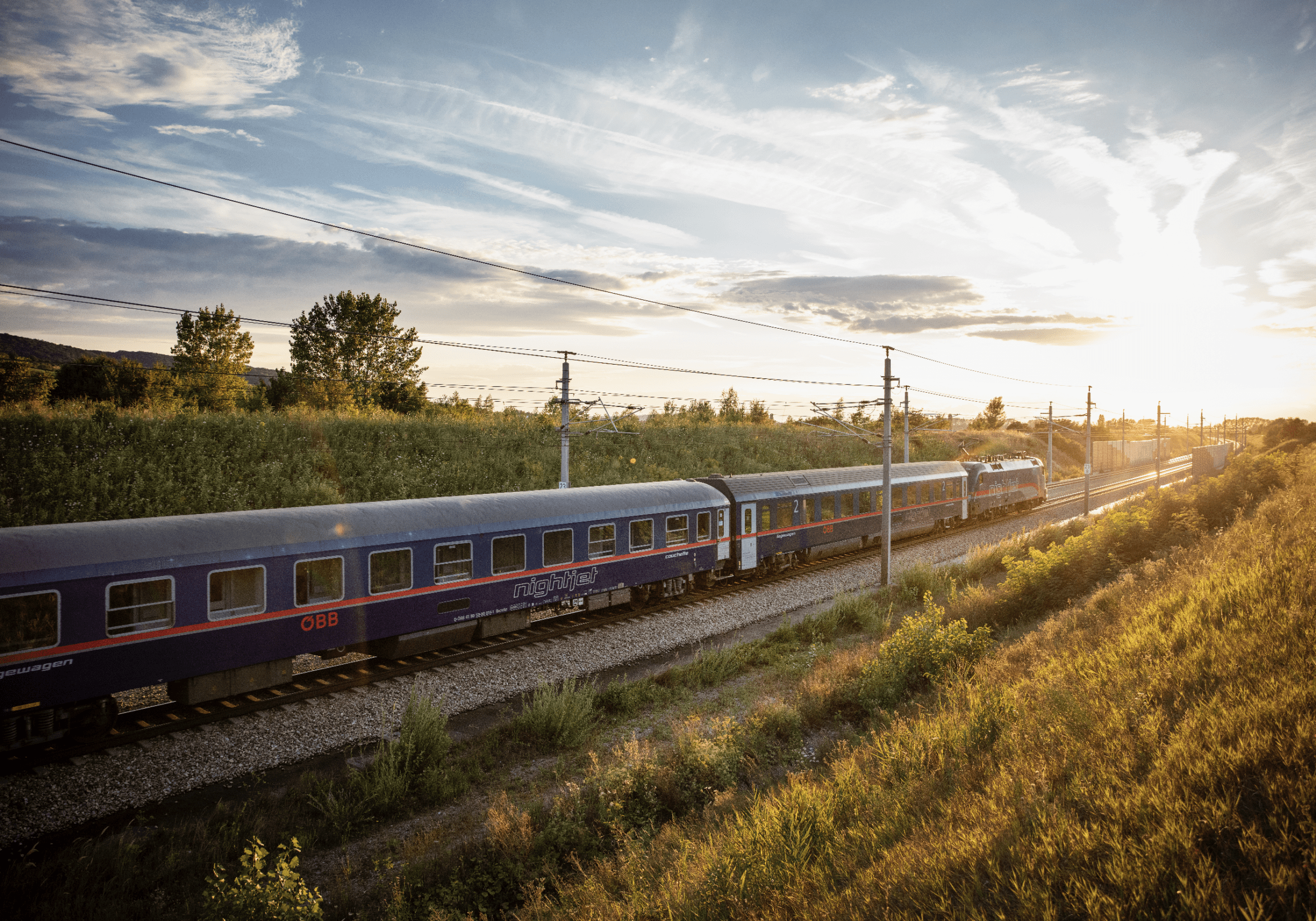 The return of European sleeper trains | The ÖBB Nightjet travelling through a green field at sunset