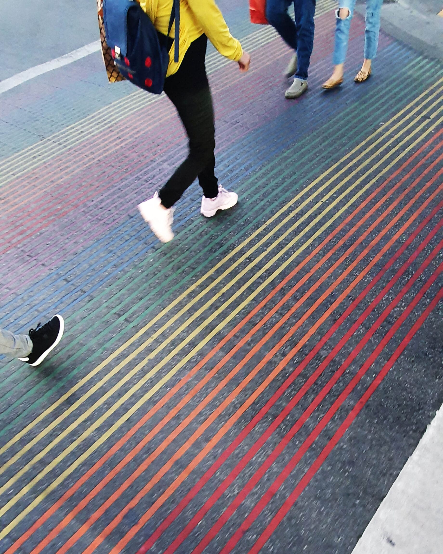 The future of queer travel | man walking on a rainbow-striped road