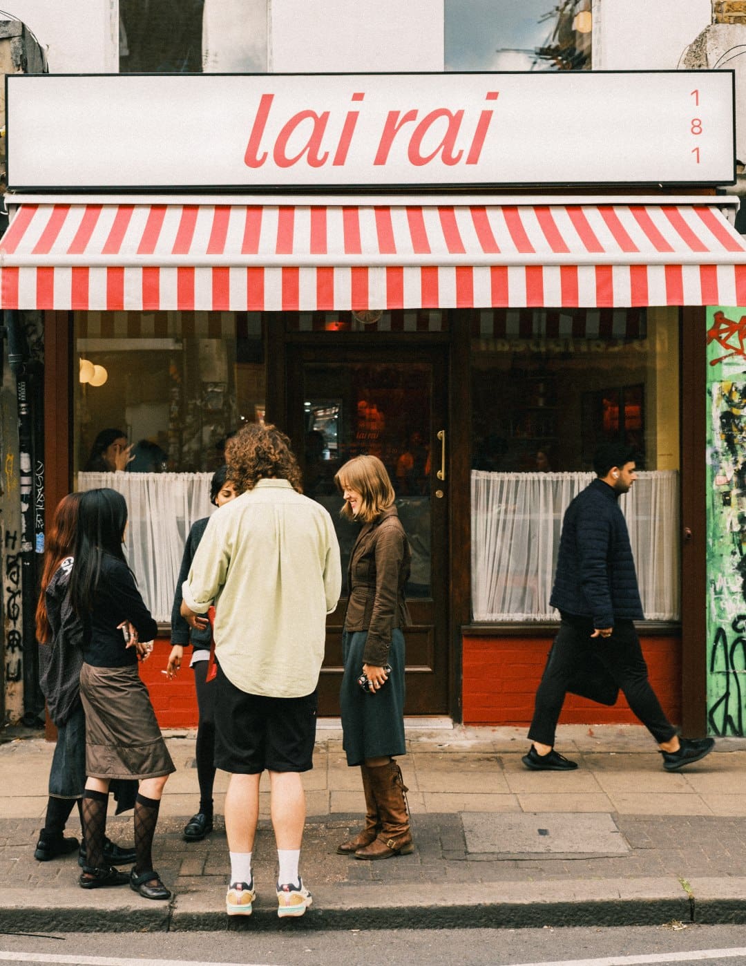 Locals outside La Rai in Peckham, with a striped awning in view