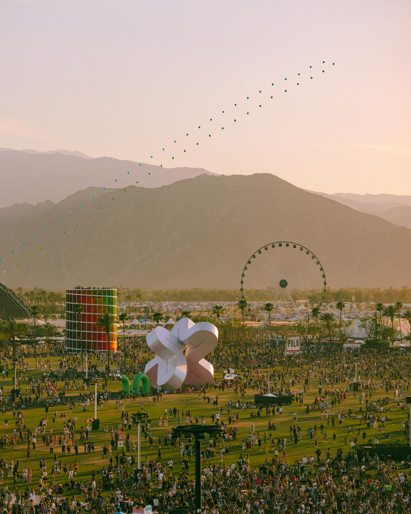 The best music festivals in the US | Coachella 2022, with art installations, a ferris wheel and crowds of people set in front of distant hills