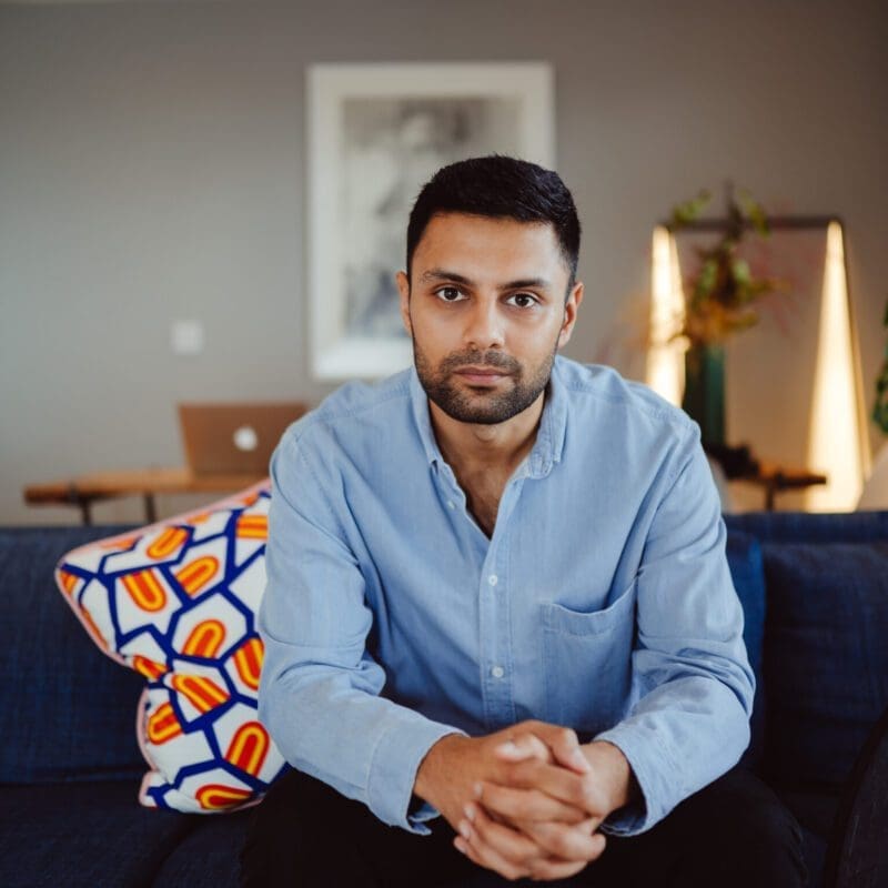 Mohsin Zaidi sits on a sofa in a blue shirt