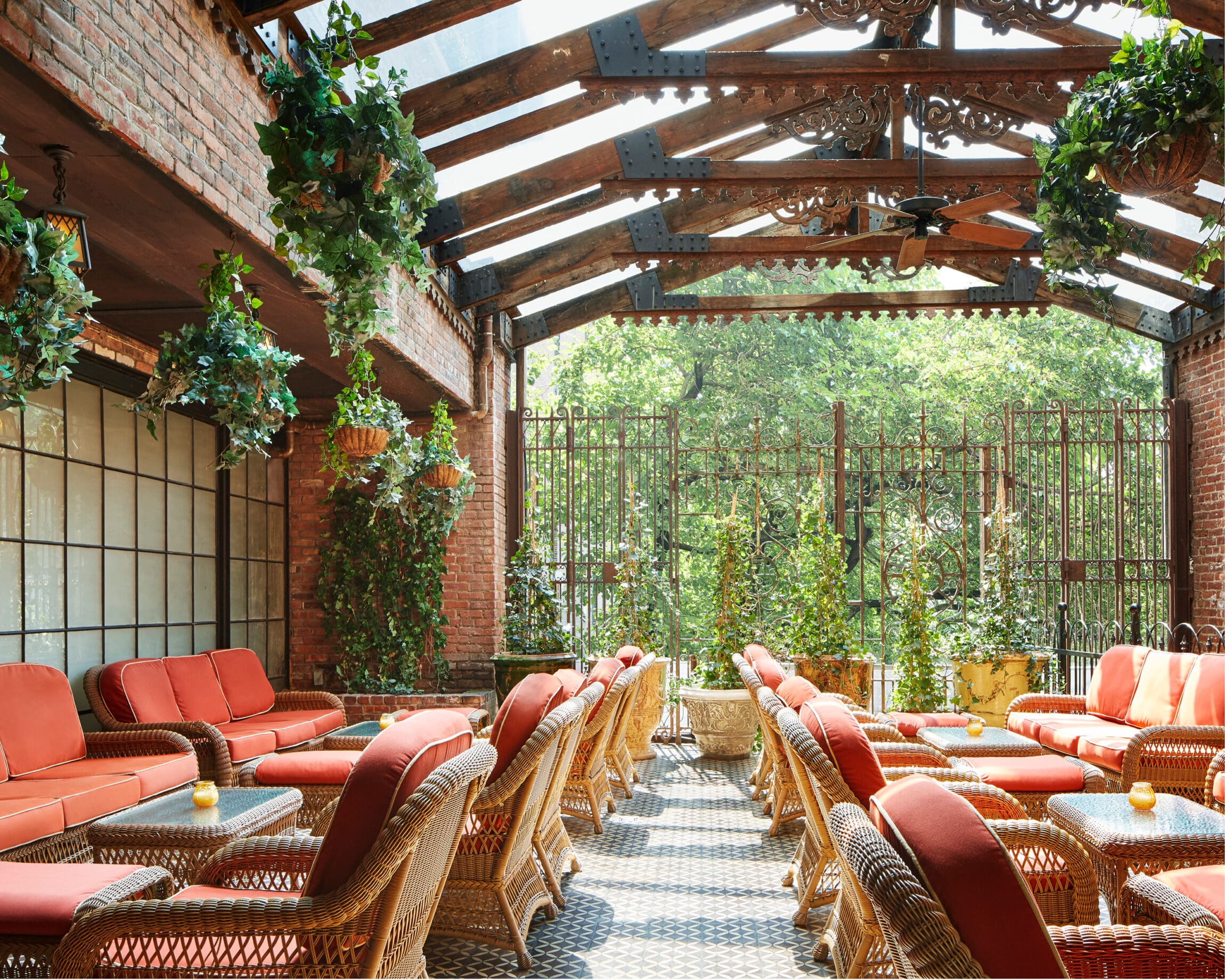 The best hotels in New York | The Bowery patio with orange cushioned seats and greenery hanging.