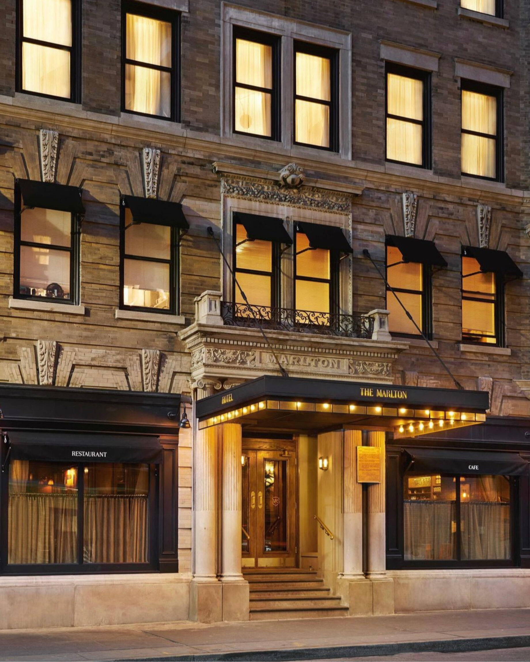 The best co-working spaces for remote working in New York City | Exterior of the Marlton Hotel with golden lighting in front of the door