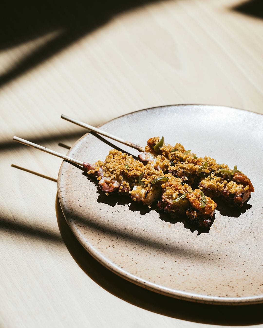 Two skewers of modern Portuguese cooking ready to enjoy on a neutral table