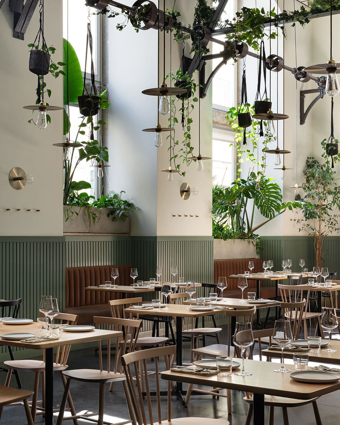 Interior of Prado restaurant. Modern, airy space with plants hanging from the ceiling