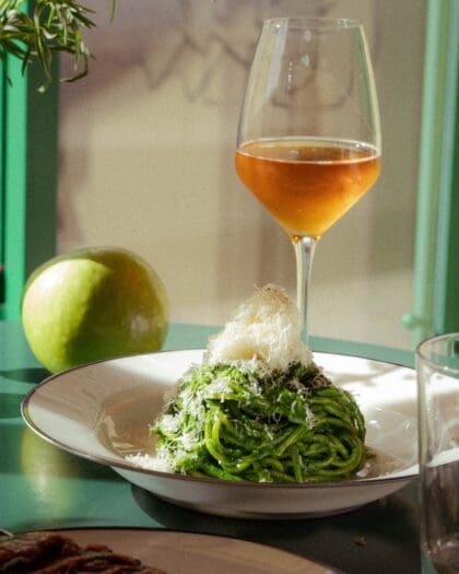 A pasta dish and glass of natural wine at Pomme