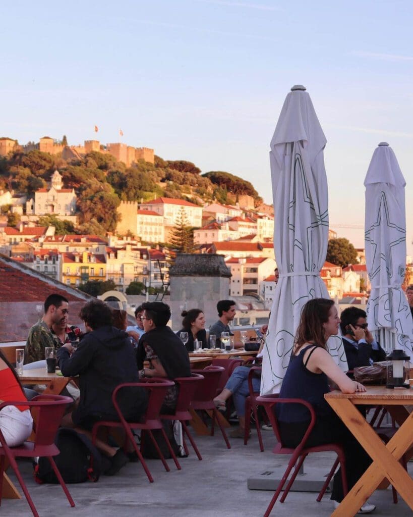 Where to watch live music in Lisbon | people sitting on a sunny terrace with building and mountain views