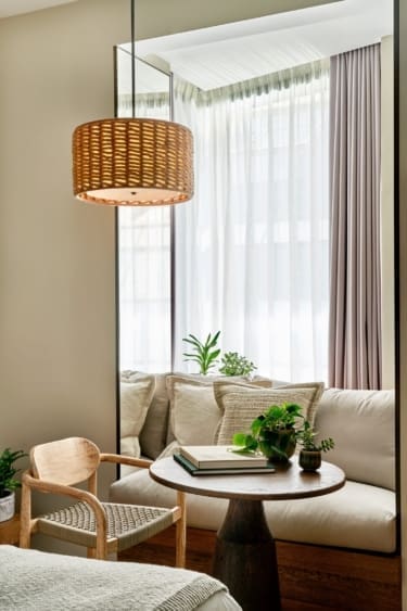 1 Hotel Mayfair | a living space with a rattan lamp and linen furnishings