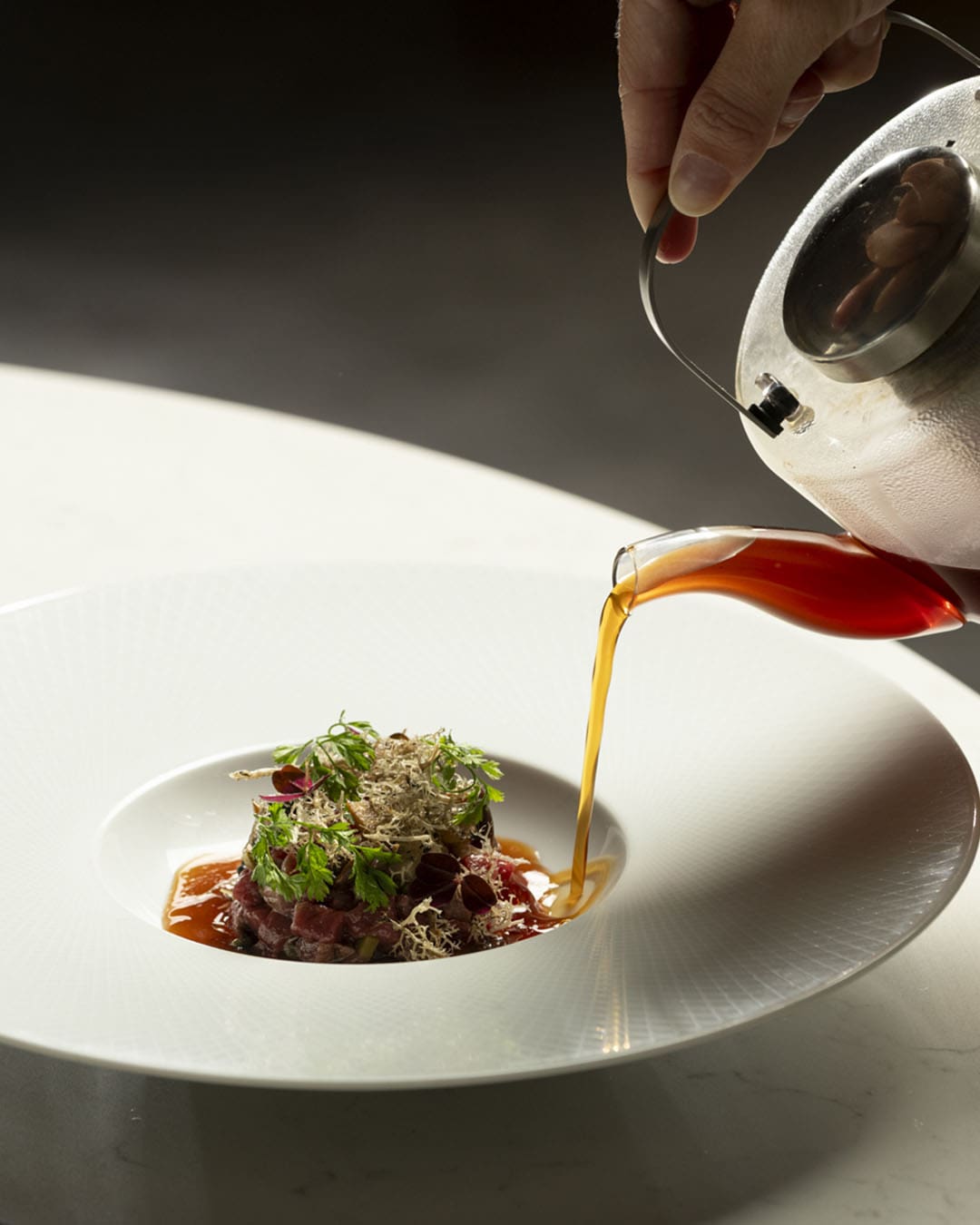 Dish and gravy being poured over with hand holding
