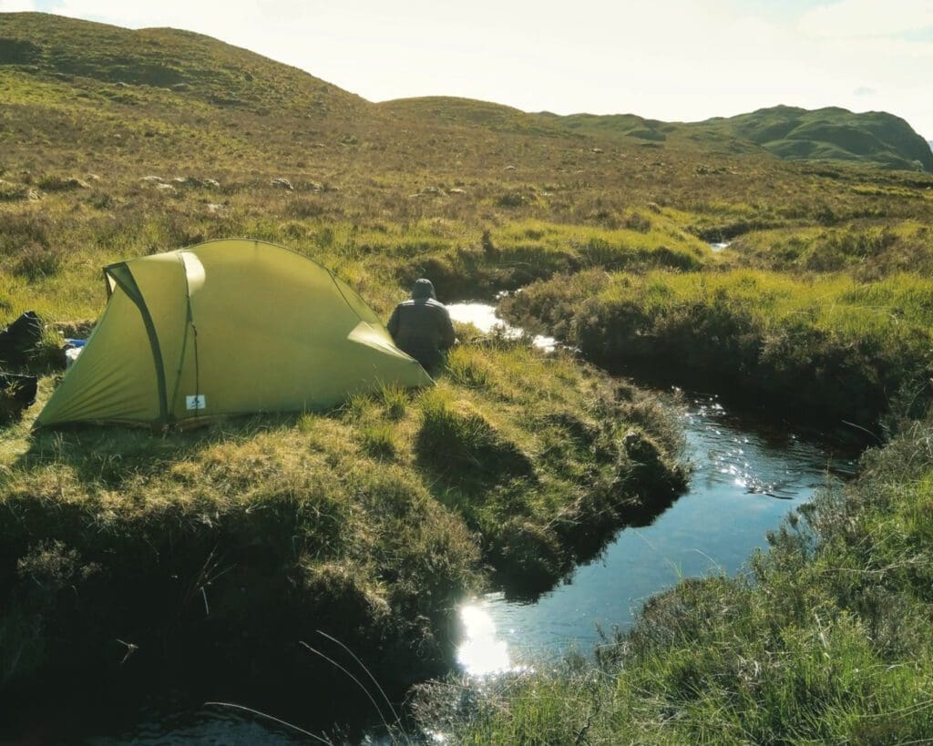 A complete guide to bikepacking in the UK | A tent pitched by a stream.