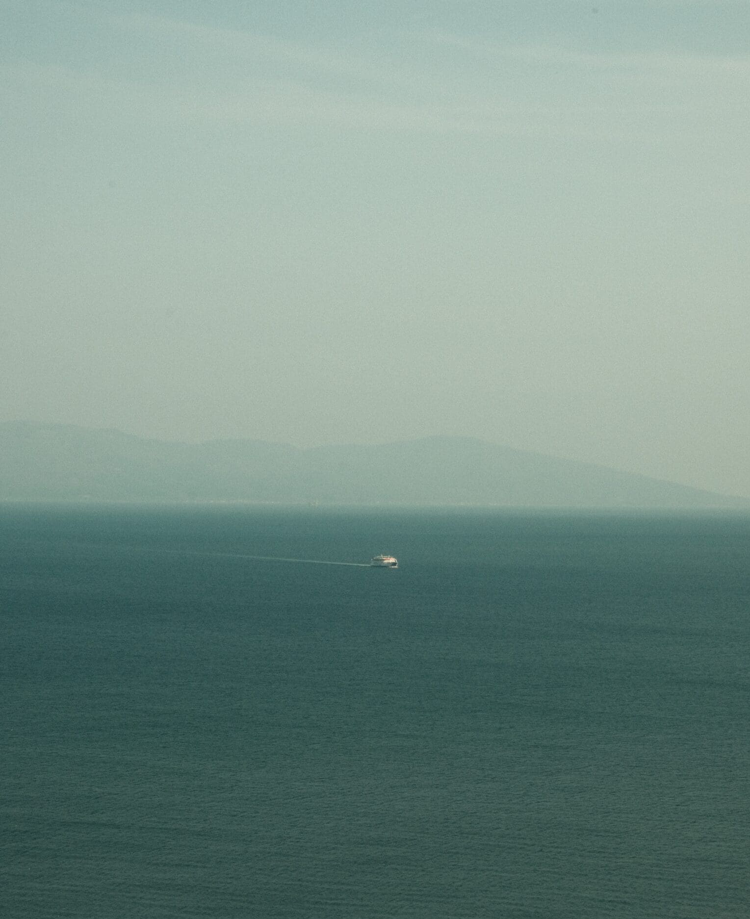 Sustainability and ferry boats | A ferry boat in the distance in the sea on a misty day