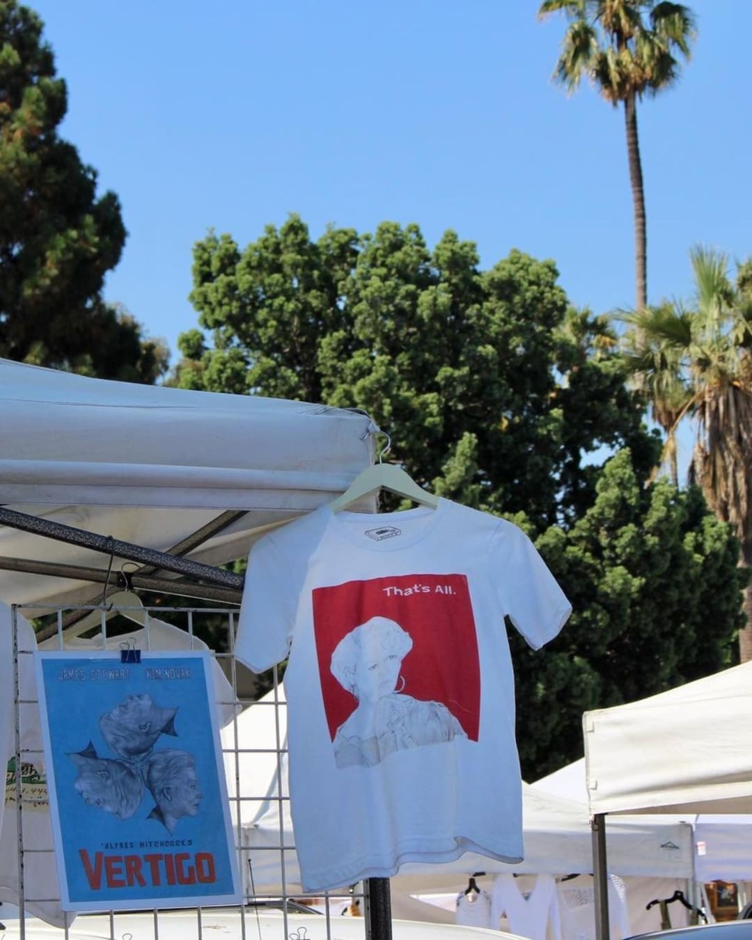 A T-shirt hung on a stall in front of a palm tree at Melrose Trading Post flea market