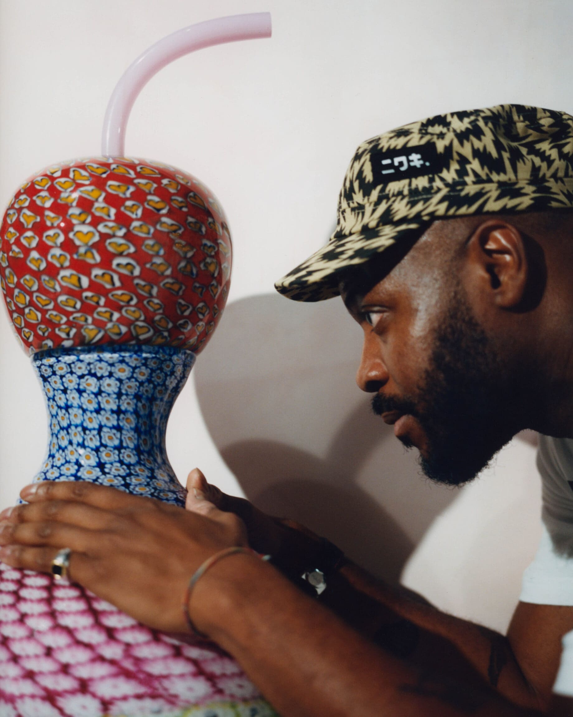 Yinka Ilori on the importance of joy and affirmation in his practice | A portrait of Yinka Ilori sat with his original murano glass sculpture.