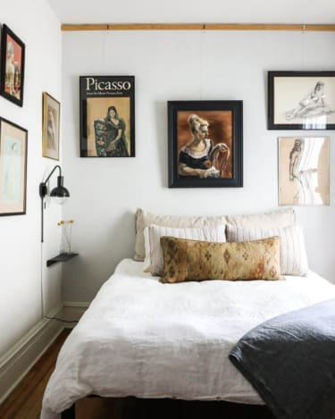 The best places to stay in Hudson | A wall of art above a bed at This Old Hudson Farmhouse