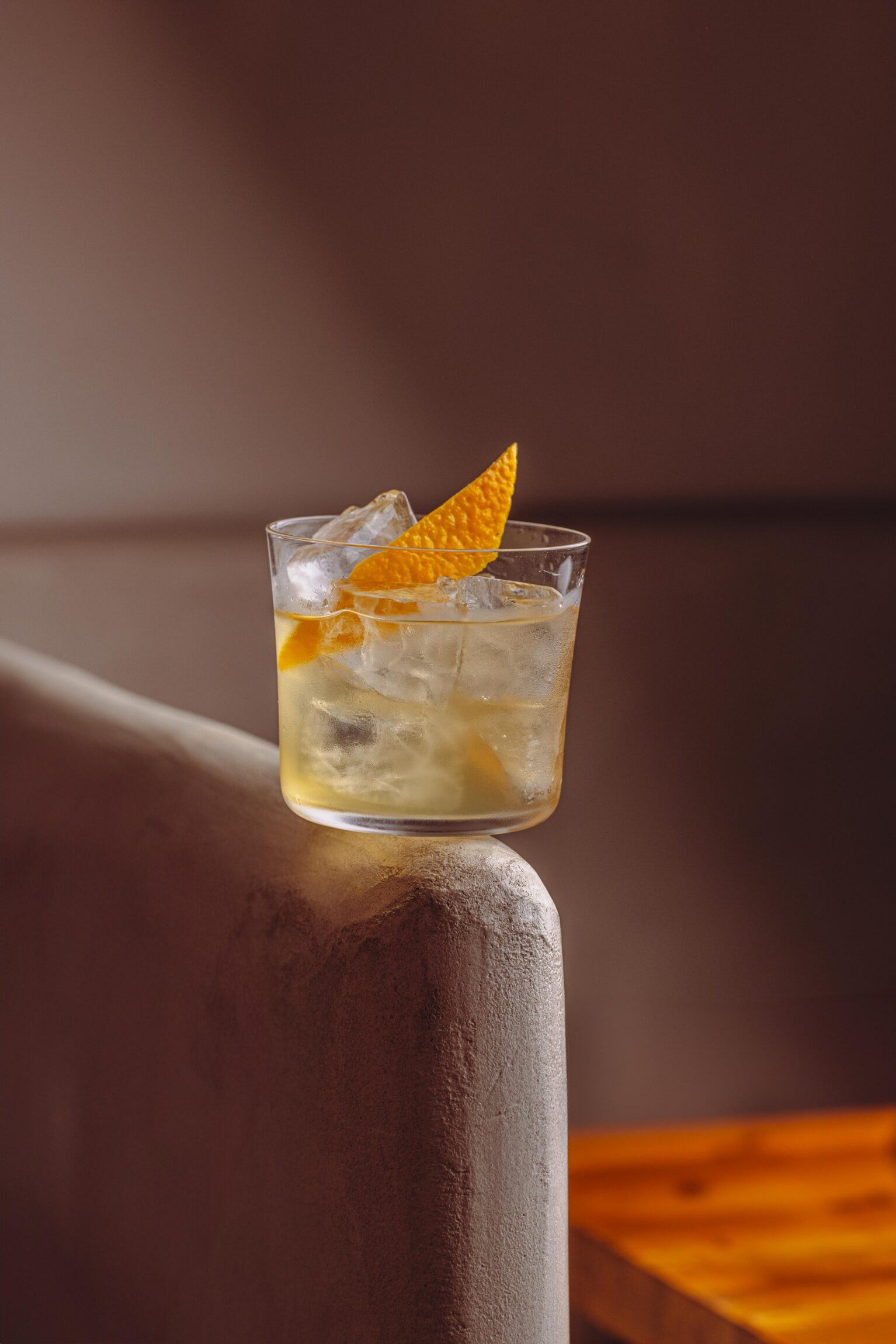 The best cocktail bars in Paris | a short drink on a sofa edge with an orange garnish
