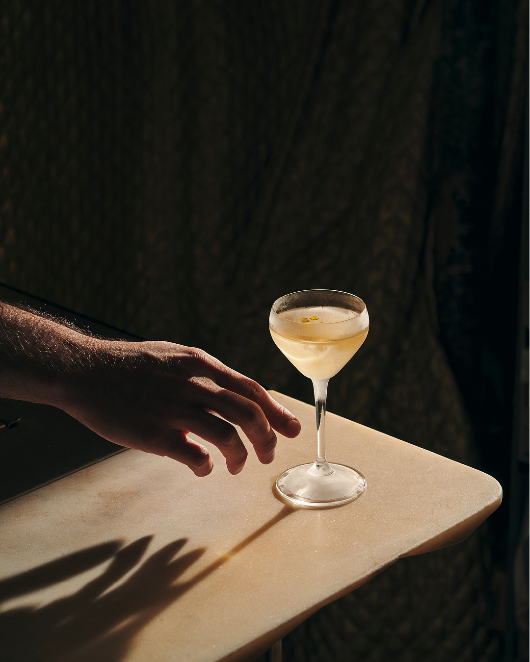 The best cocktail bars in Paris | a glowing drink against a dark curtain at Le Syndicat