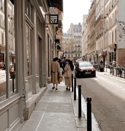 Two people strolling down a traditional Parisian street alongside vintage shop Thanx God I'm a VIP