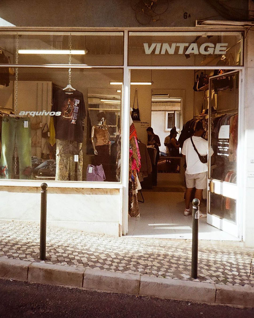 Arquívos shop front in Lisbon, with the word 'VINTAGE' embossed upon the glass entrance, with a cobbled street outside.
