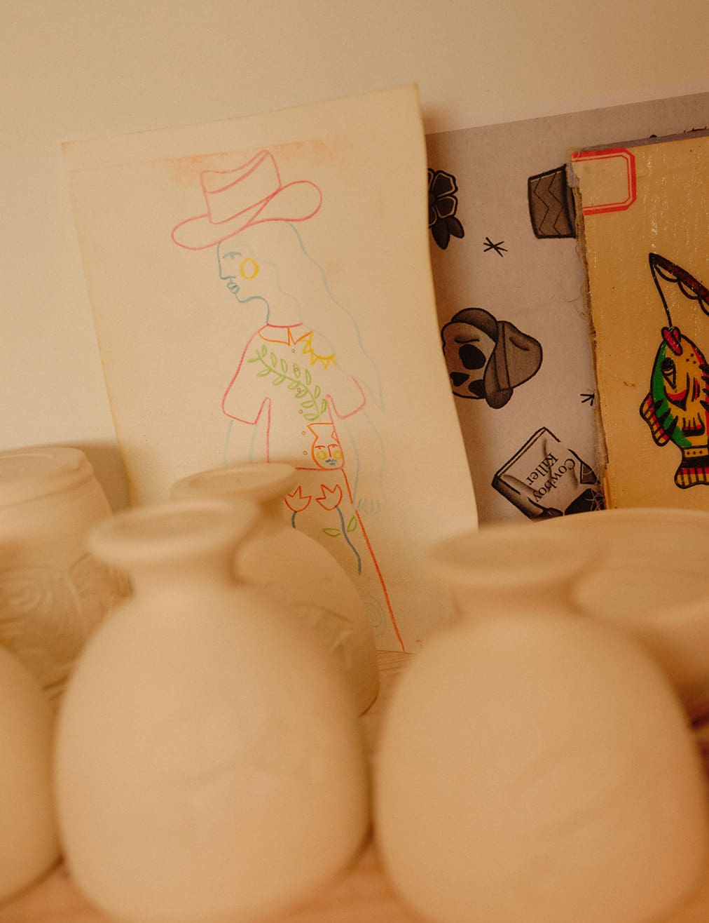 How Did I Get Here with Daniel Dooreck of Danny D's Mud Shop | Unpainted vases resting in the studio with illustration ideas sketched on paper behind.