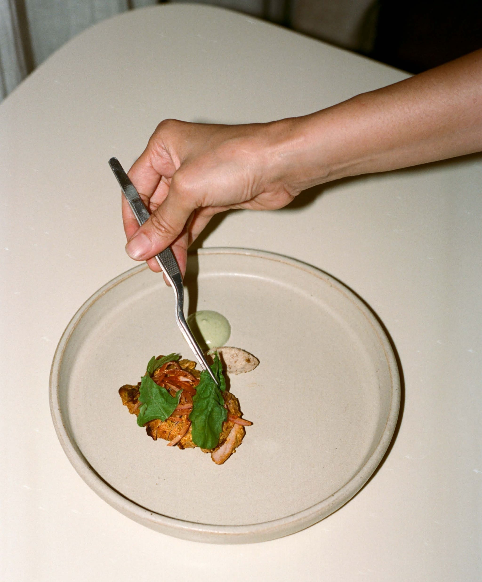 Plating up food on a white plate at Noon.
