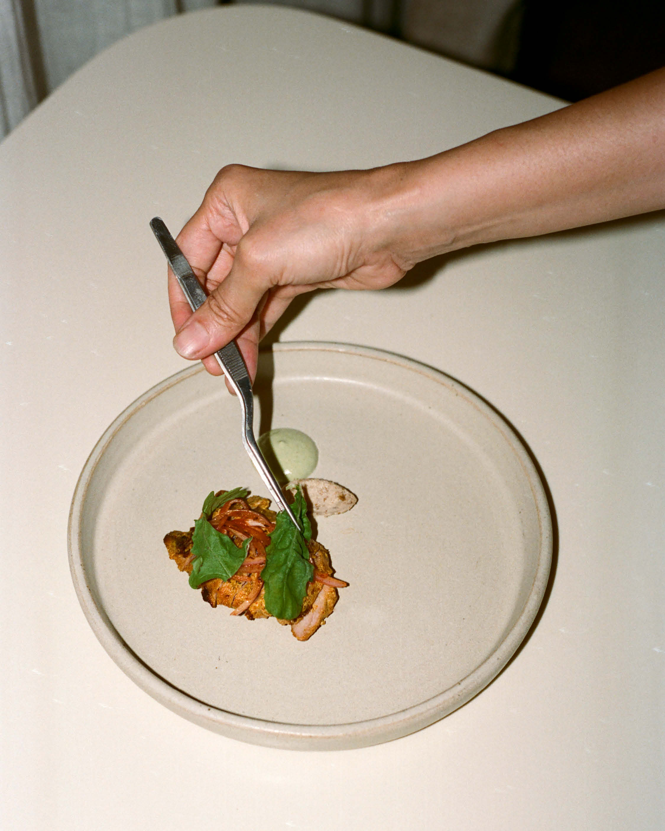 Plating up food on a white plate at Noon.