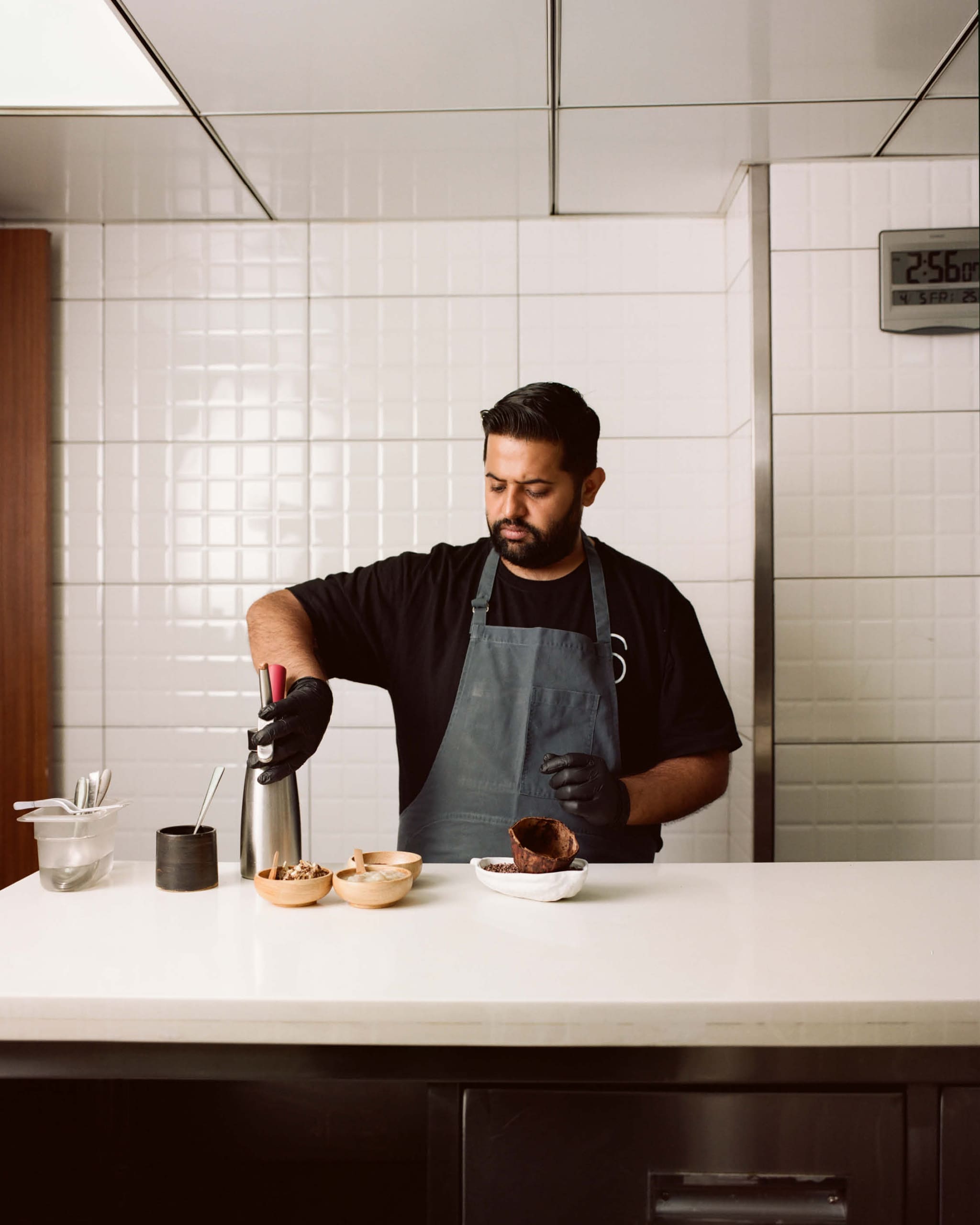 Varun Totlani working at his restaurant Masque at a white countertop.
