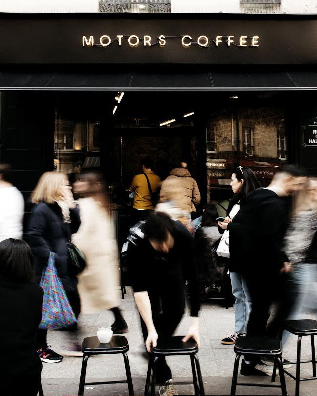 The black frontage of Motors Coffee with coffee drinkers inside and out