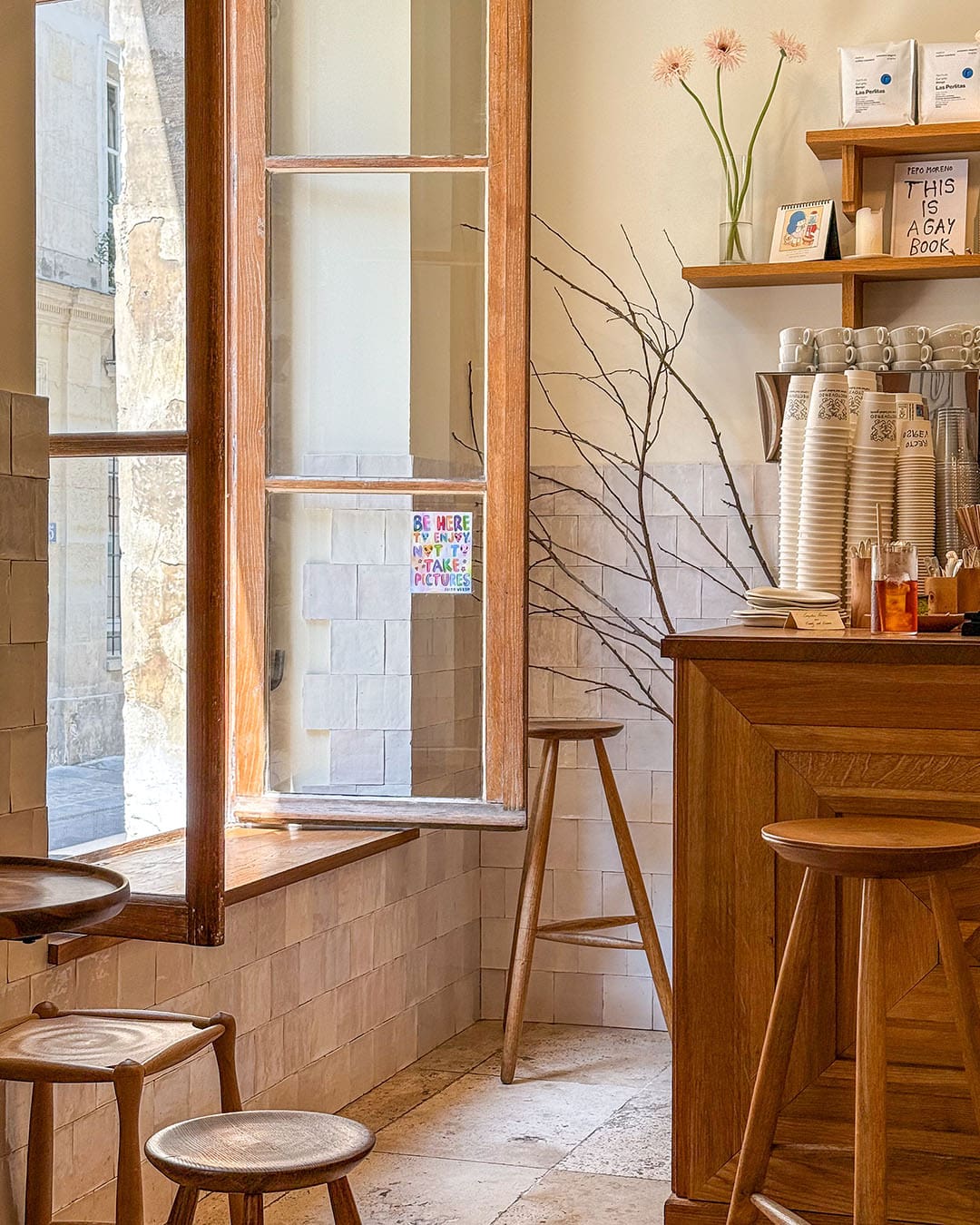 Interior of Recto Verso, a Parisian coffee shop with wooden table, open window and coffee machine. Light and airy with a witty sign on the window which says