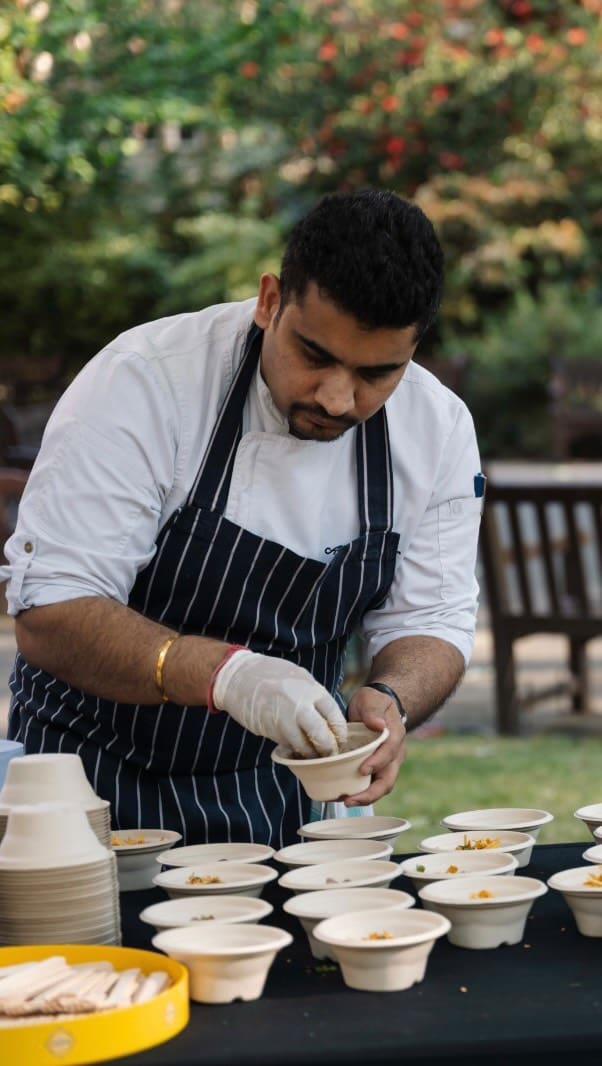 A chef plates up in a garden setting