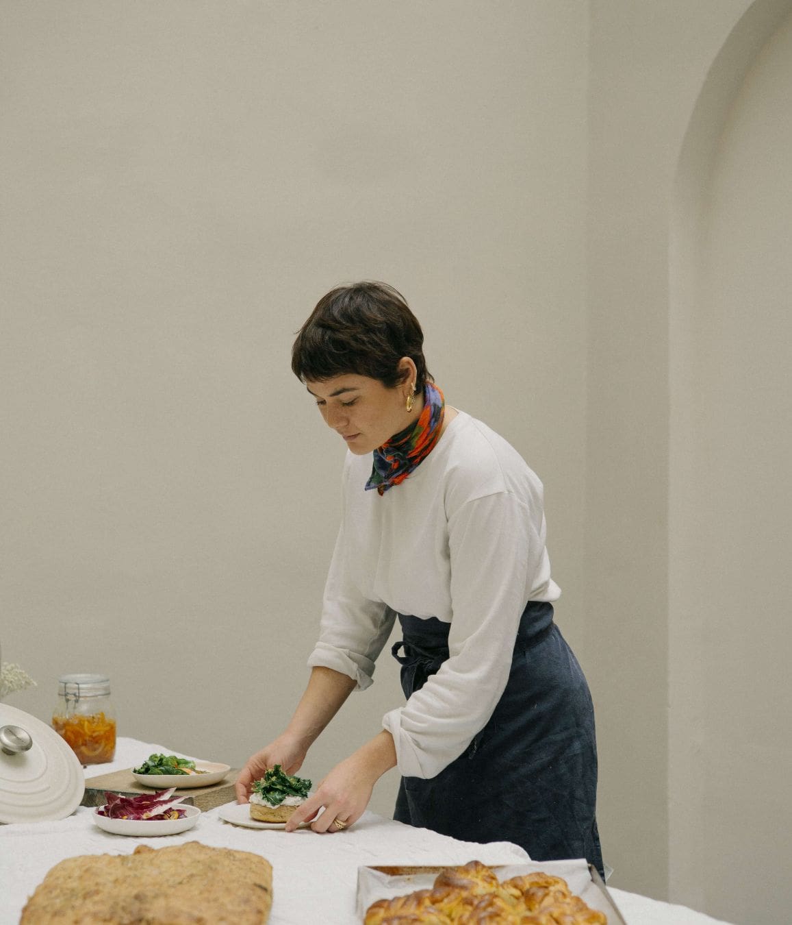 A woman resident chef plates freshly made food in a whitewashed Italian setting