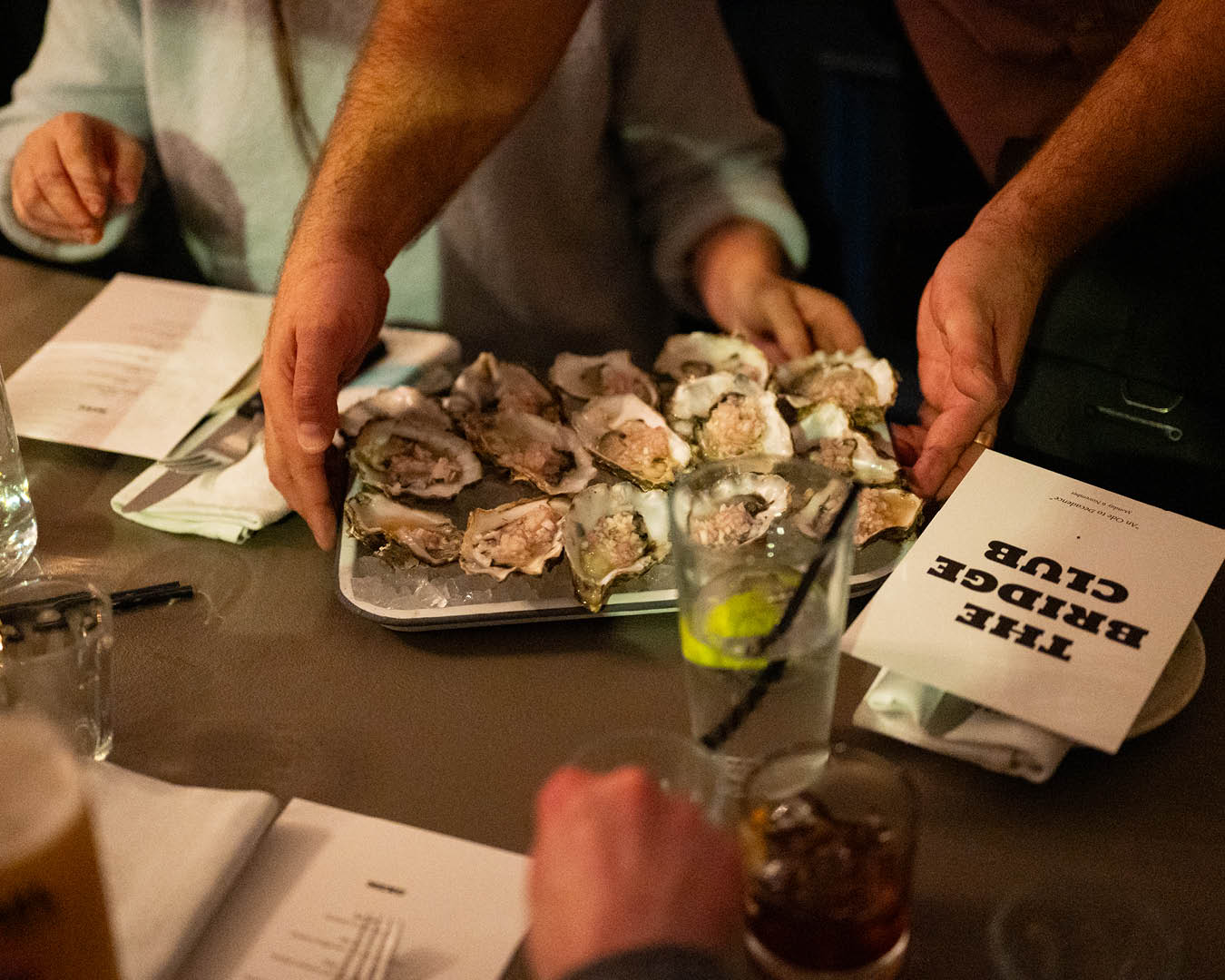 Platters of food, beer, wines, and candles line the table at a Bridge Club dinner