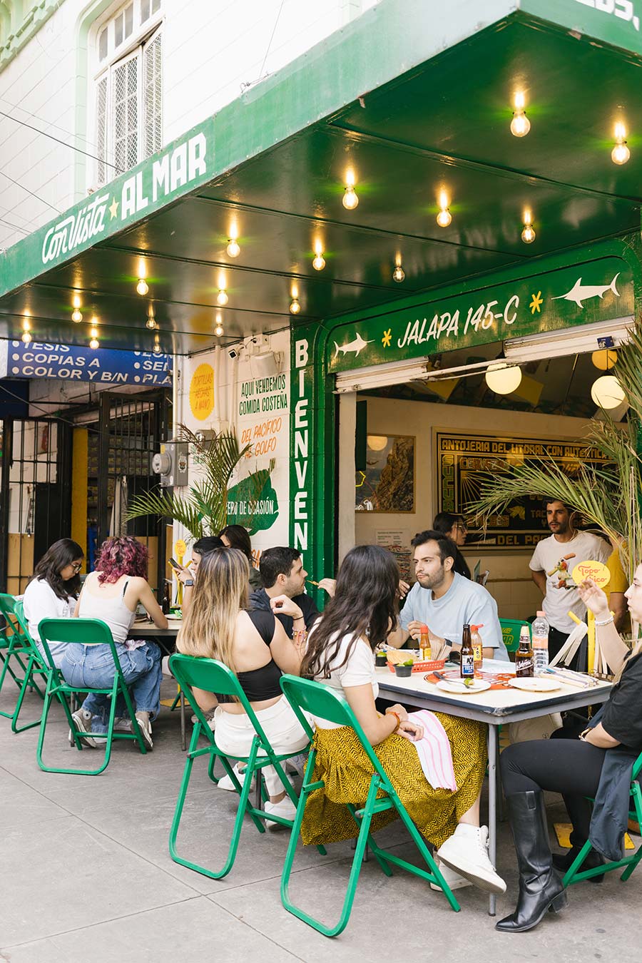 Peopel sat at outdoor tables at Con Vista al Mar food stall