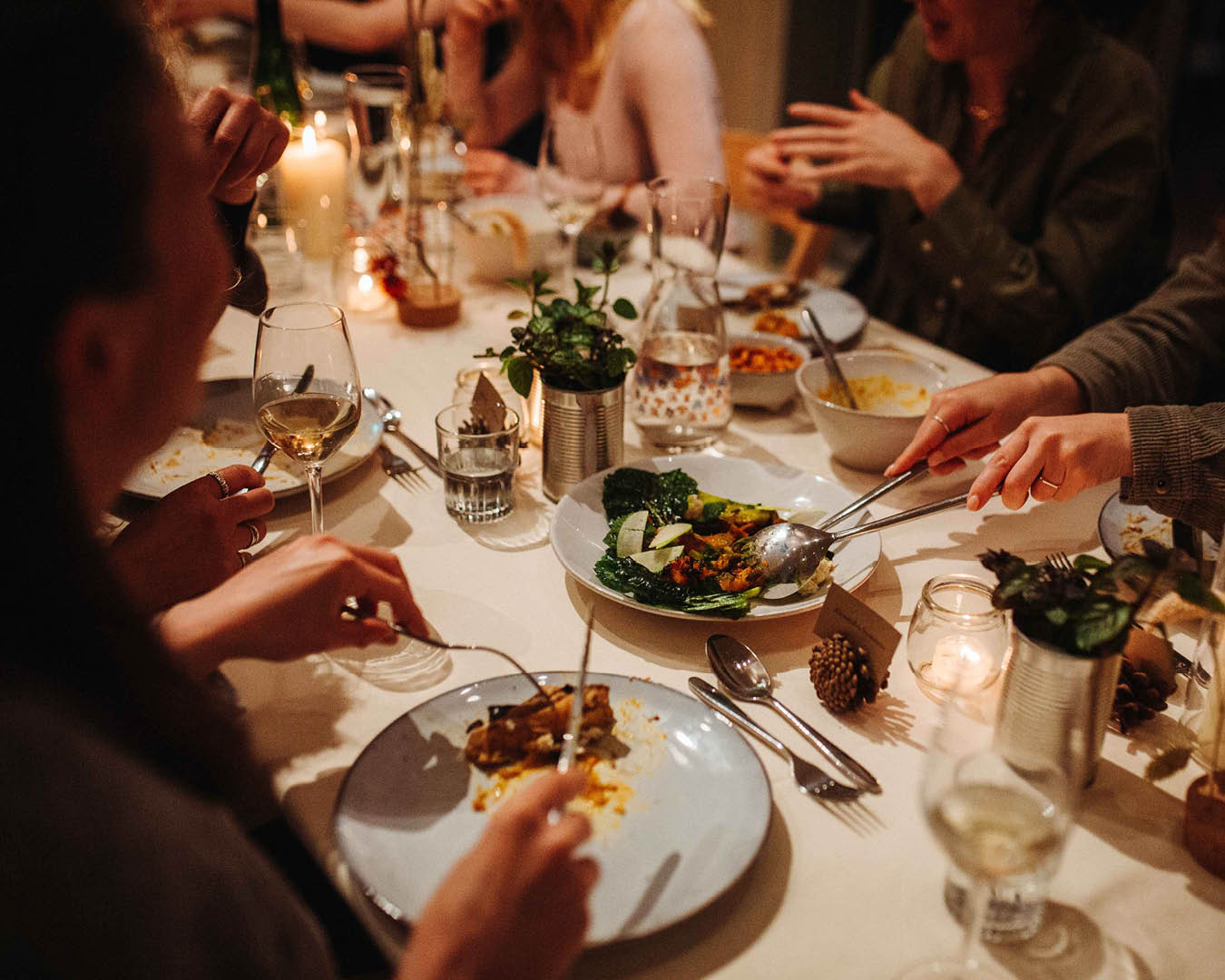 A group of people gathered around a table lined with wines and fresh food