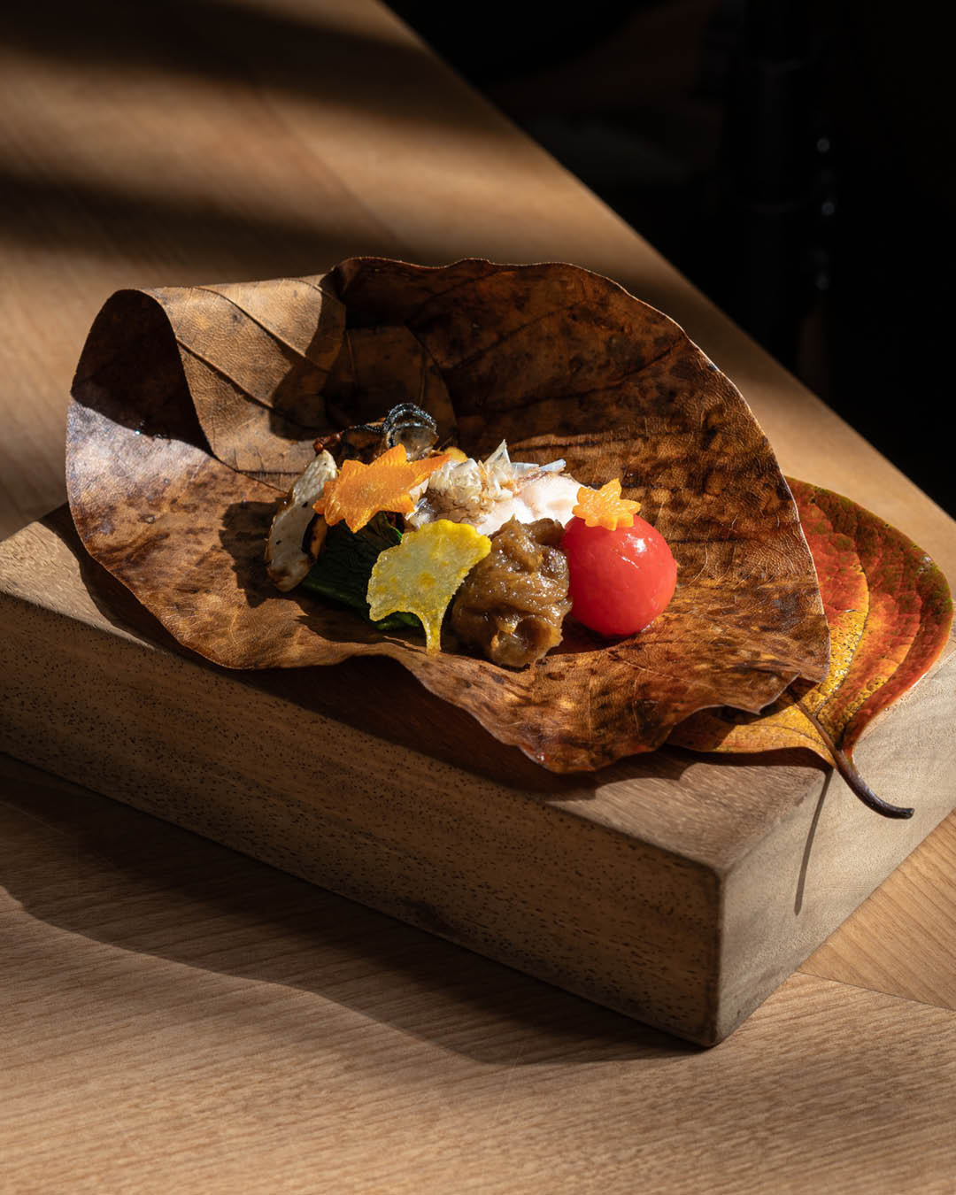 A starter served on a leaf on a wooden block at Hashida, Singapore.
