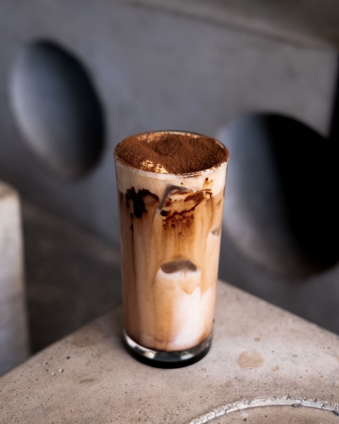 An iced mocha in a tall glass, served on a zinc table at Karo Coffee Roasters.