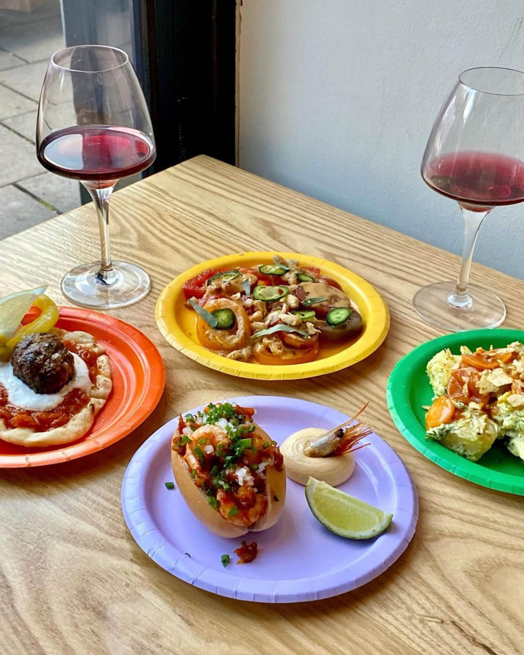 Colourful plates and glasses of red wine at a Mam Sham pop-up at Peckham Cellars