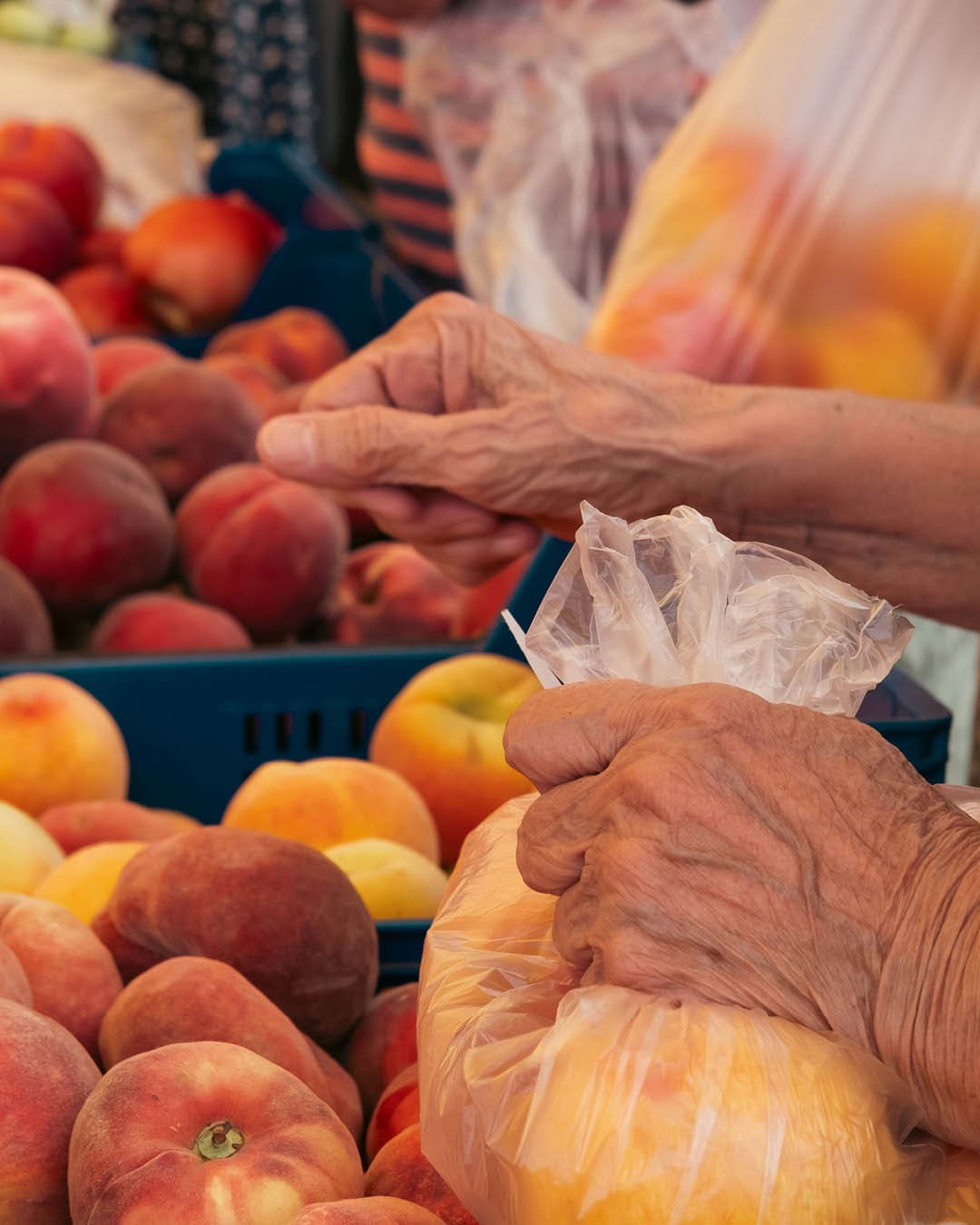 Elderly lady buys fresh peaches in a market